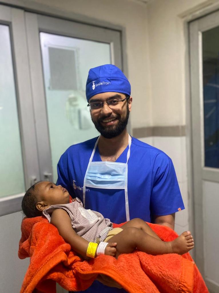 Dr Parth Guar smiling and holding a baby patient