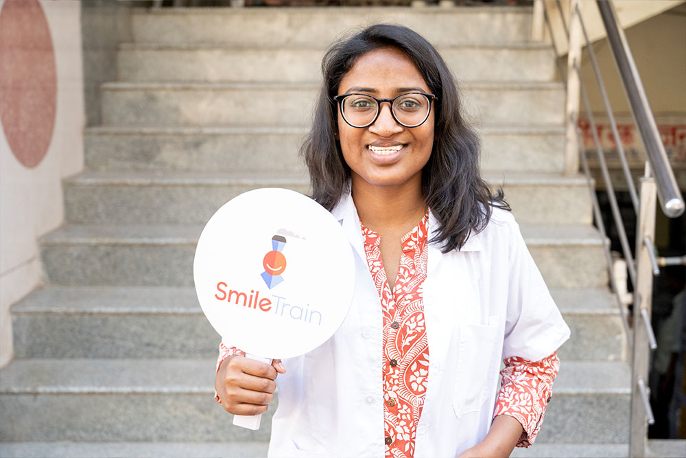 Dr Mayuri Kalyanpad smiling and holding a Smile Train sign after cleft surgery