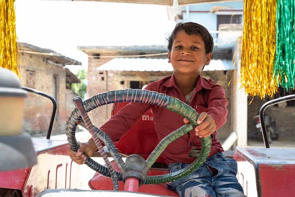 Shubham smiling and holding a steering wheel after cleft surgery