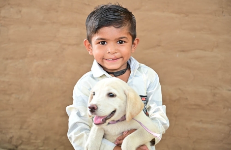 Jairaj smiling and holding a dog after cleft surgery