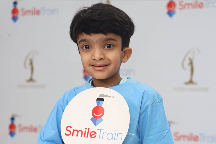 Smile Train patient holding Smile Train logo