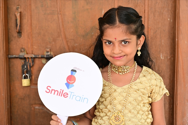 Pravallika smiling and holding a Smile Train sign after cleft surgery