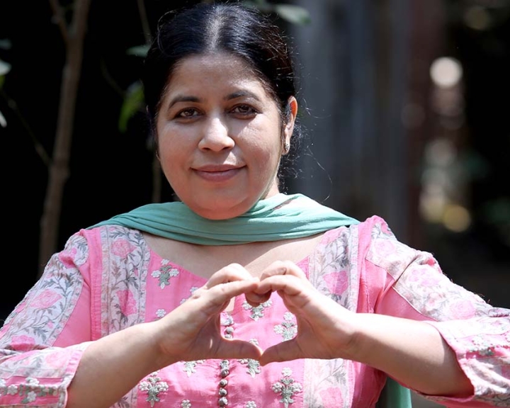 Dr Bharti Khandelwal smiling and holding up the International Women's Day heart sign