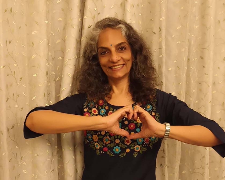 Dr Anjali Saple smiling and holding up the International Women's Day heart sign