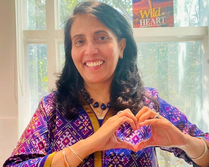 Mamta Carroll smiling and holding up the International Women's Day heart sign