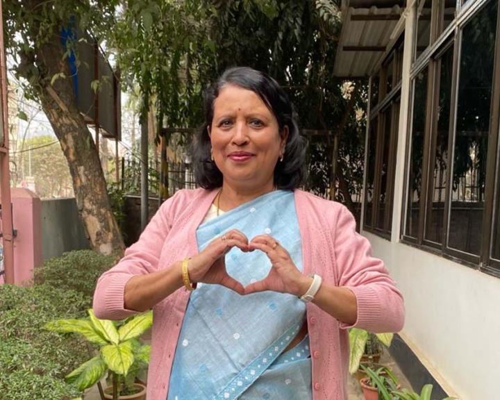 Prod. Dr Seema Rekha smiling and holding up the International Women's Day heart sign