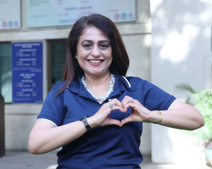 Renu Mehta smiling and holding up the International Women's Day heart sign