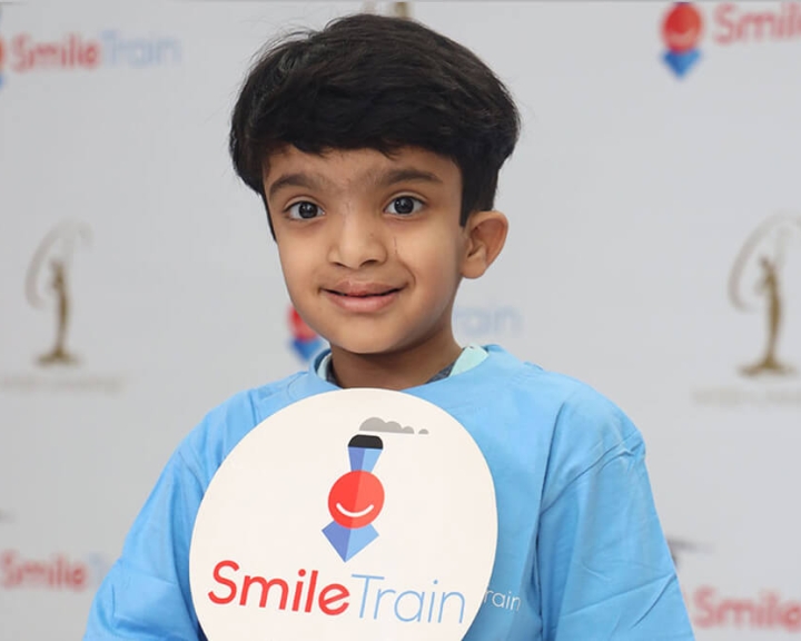 Smile Train patient holding Smile Train logo