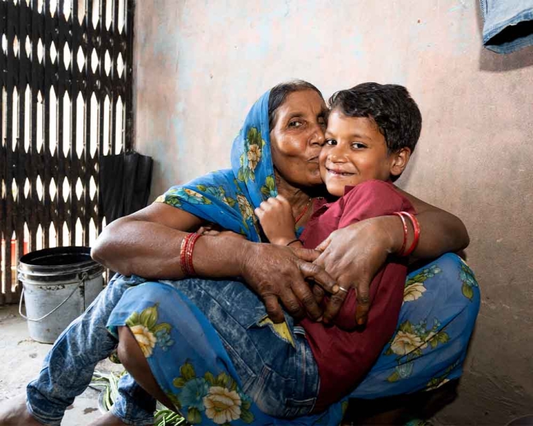 Shubham in his grandmother's lap being hugged and kissed by her after cleft surgery
