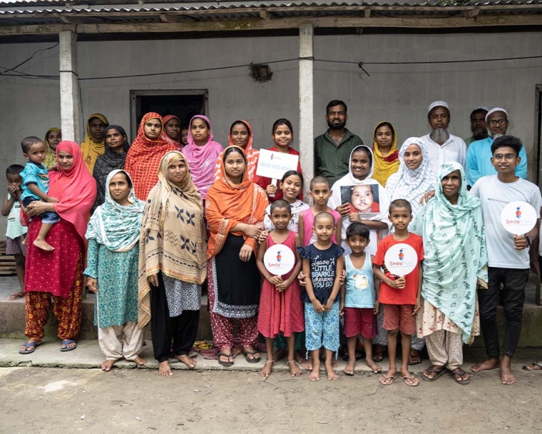 Rajiya smiling with her family holding signs after her cleft surgery