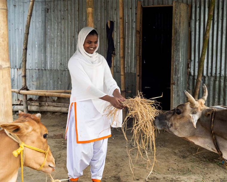 Rajiya smiling and feeding her cattle after cleft surgery