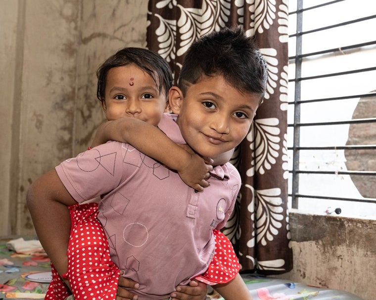 Abhay smiling and giving his sister a piggyback after cleft surgery